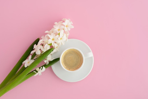 Cup of coffee and spring flower on pink table top view espresso
flowers on pink pastel background