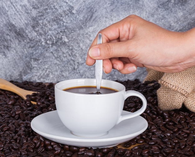 Cup of coffee stirred by hand