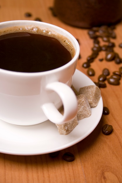 Cup of coffee, sugar and beans on wooden table