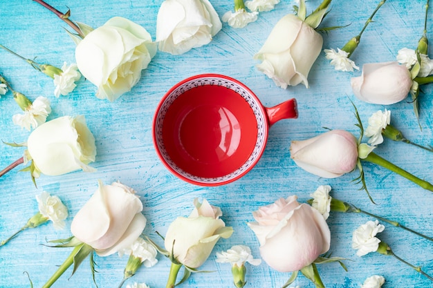 Cup of coffee surrounded by white roses