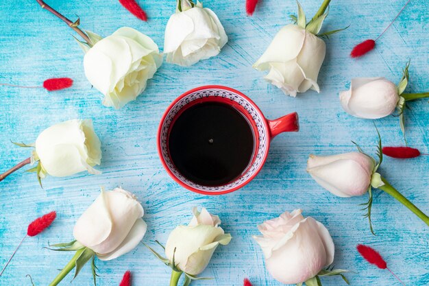 Cup of coffee surrounded by white roses