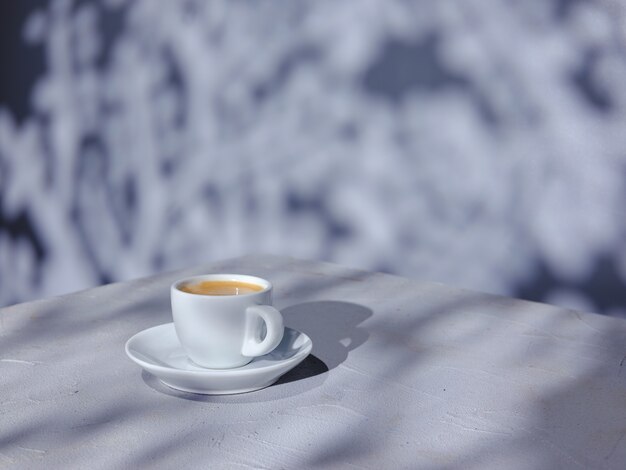 Cup of coffee on the table with natural light and shadow