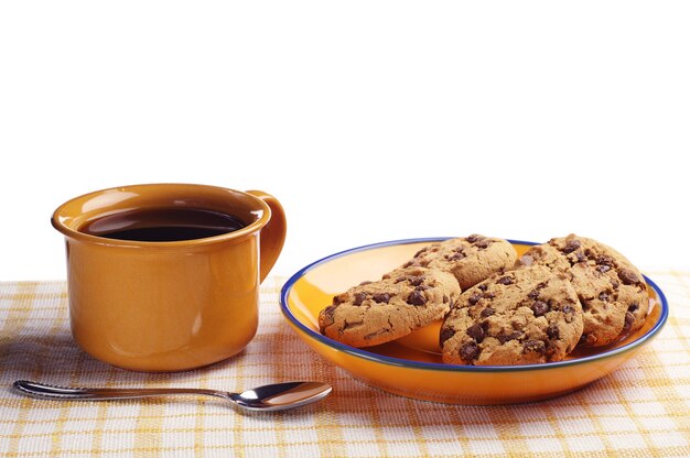 テーブルクロスの上のコーヒーとおいしいチョコレートクッキーのカップ