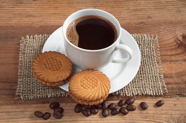 Cup of coffee and tasty cookies with cream filling