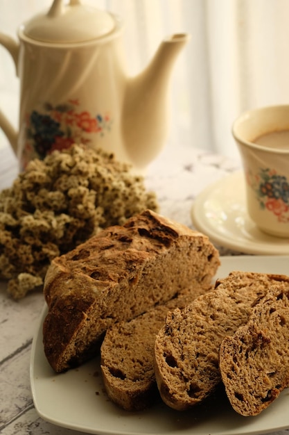 a cup of coffee, teapot, and sliced sourdough brown bread. on a wooden table. breakfast. Gluten free