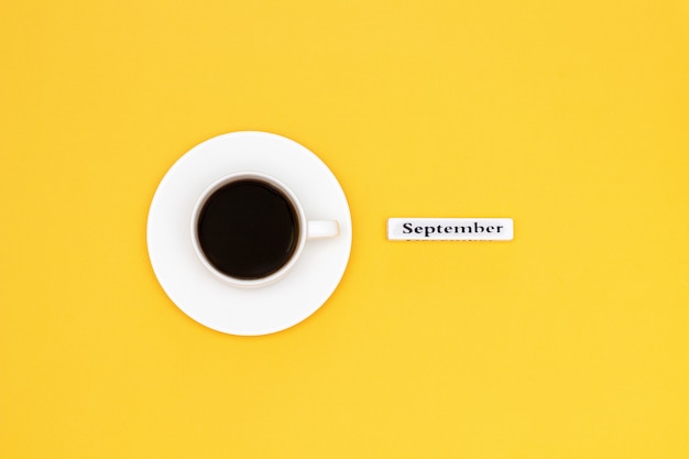 Cup of coffee and text September on yellow background