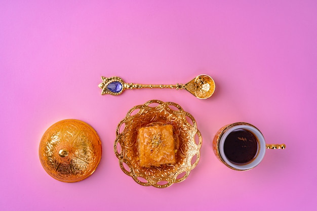 Cup of coffee and turkish dessert baklava on pink