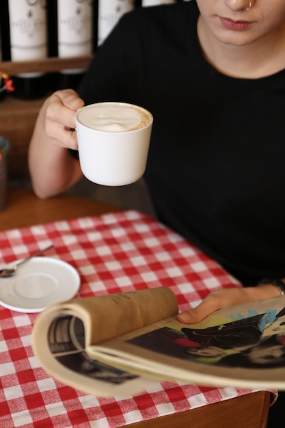 Foto una tazza di caffè mentre si legge un libro o una rivista