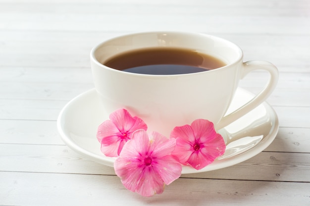 Cup of coffee on a white table and flowers of pink Phlox. 