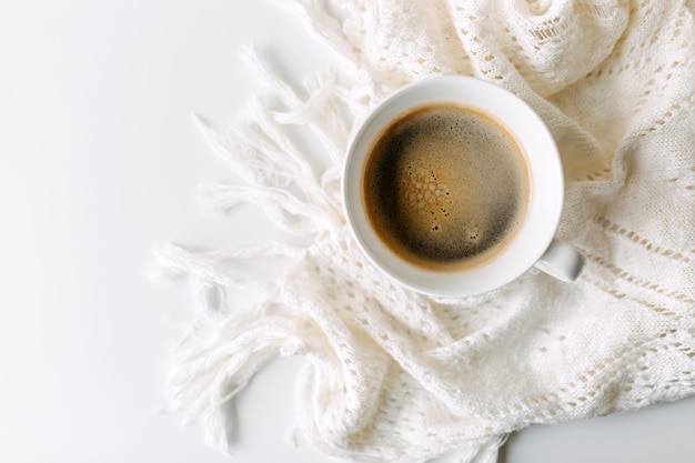 Cup of coffee on white table with a crochet blanket