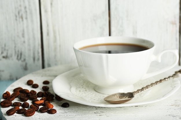 素朴な木製の背景の色に豆とコーヒーのカップ
