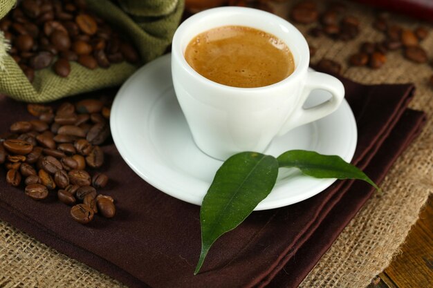 Cup of coffee with beans on table close up