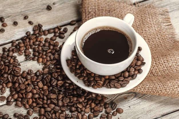 Cup of coffee with beans on table