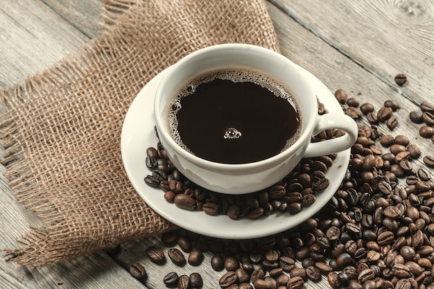 Cup of coffee with beans on table