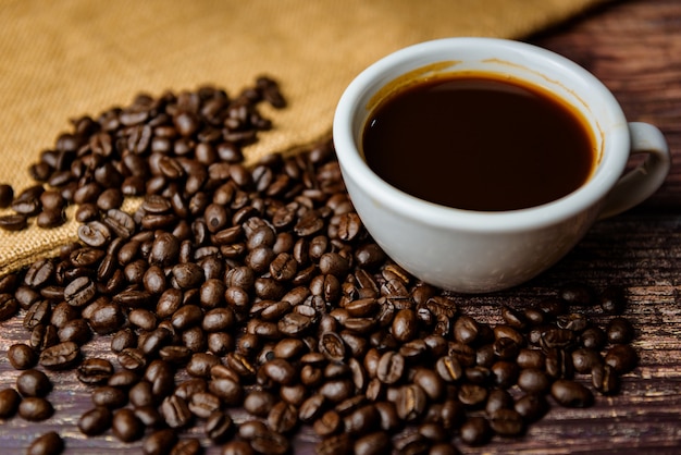 Cup of coffee with beans on wooden background 