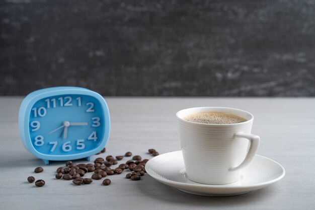 cup coffee with blue alarm clock.