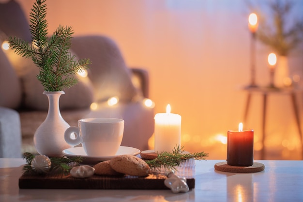 Чашка кофе с зажженными свечами и рождественскими украшениями дома