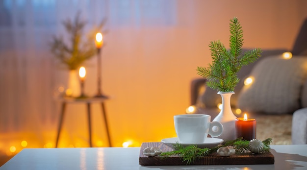 Чашка кофе с зажженными свечами и рождественскими украшениями дома