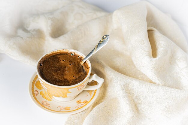 Cup of coffee with chocolate on a light white table and beige napkin Breakfast coffee in bed