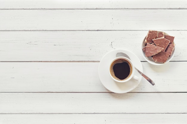 Cup of coffee with chocolate on wooden table.