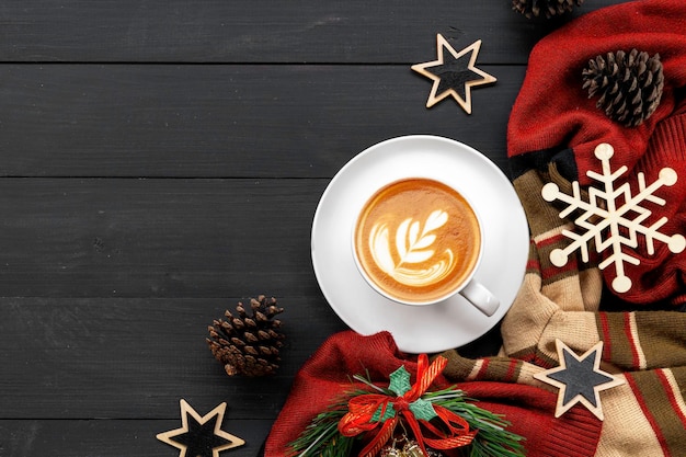 Cup of coffee with christmas decorations on black wooden table top view