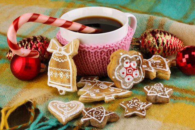 Cup of coffee with Christmas sweetness on plaid close-up