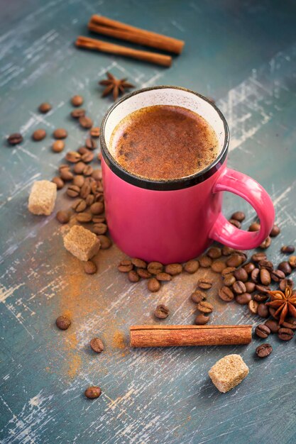 Tazza di caffè con cannella, chicchi di caffè e spezie.