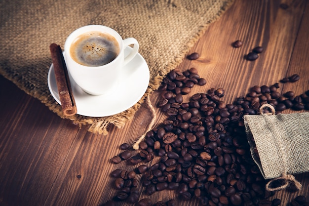 Cup of coffee with coffee beans and canvas with cinnamon