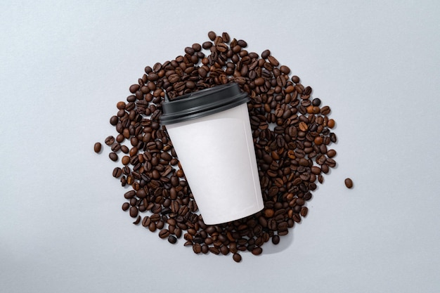 Cup of coffee with coffee beans on paper background top view