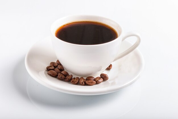 A cup of coffee with coffee beans on a plate, isolated on white.