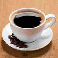 Photo cup of coffee with coffee beans on sackcloth background close up
