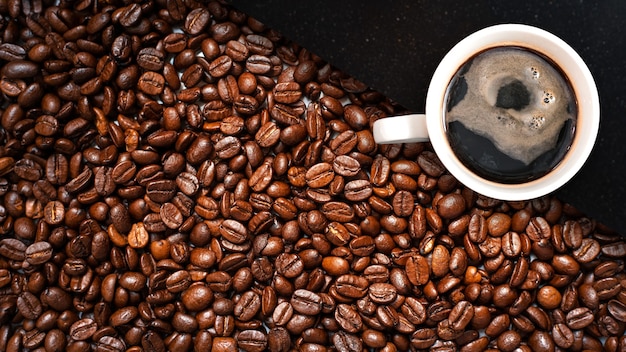 Cup of coffee with coffee beans on table