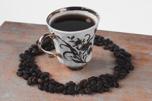 Cup of coffee with coffee beans on a wooden board, white background.