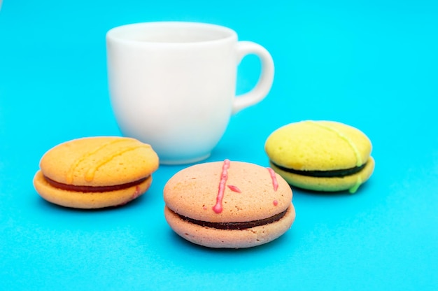 Cup of coffee with colorful macaroons on blue