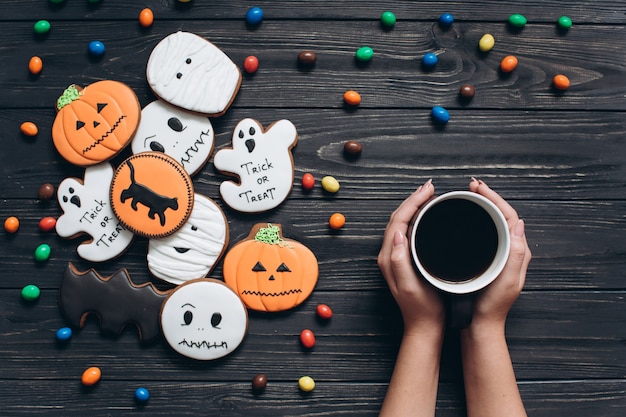 A cup of coffee with colors candy and scary gingerbreads on the Halloween.