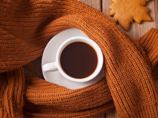 Cup of coffee with cookie and brown sweater on the wooden table