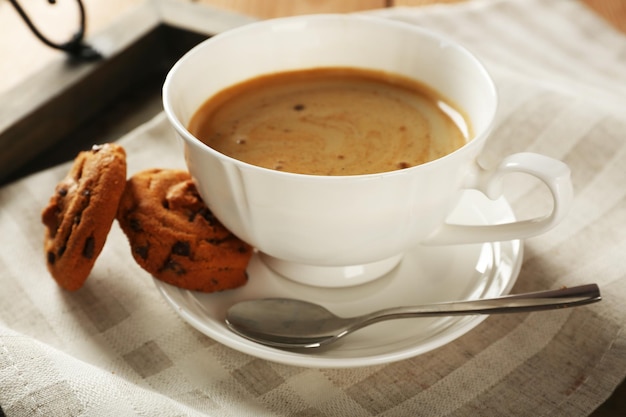 Cup of coffee with cookie on table closeup