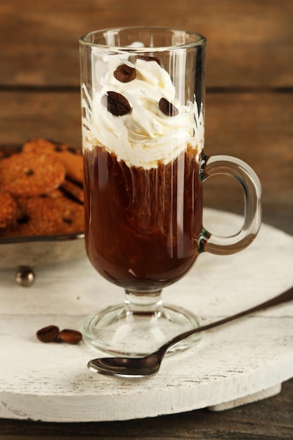 Cup of coffee with cream and cookies on wooden background