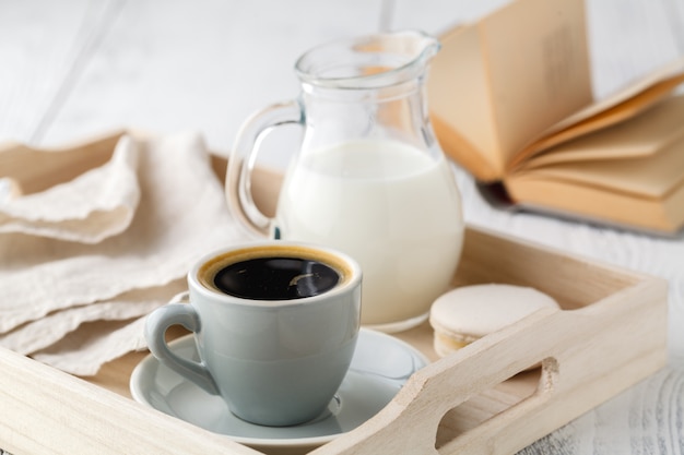 Cup of coffee with cream on wooden tray