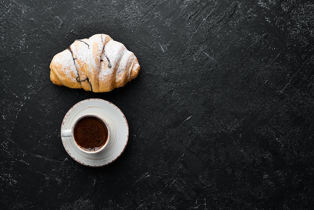 Cup of coffee with croissant Breakfast On a black stone background Top view Free space for your text