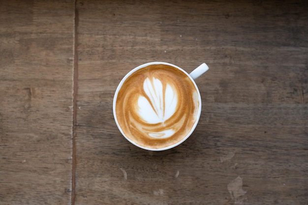 A cup of coffee with a flower design on the top.