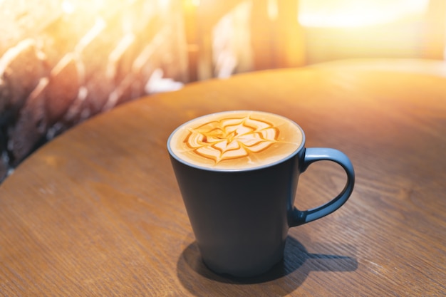 Cup of coffee with flower shaped froth on wooden table