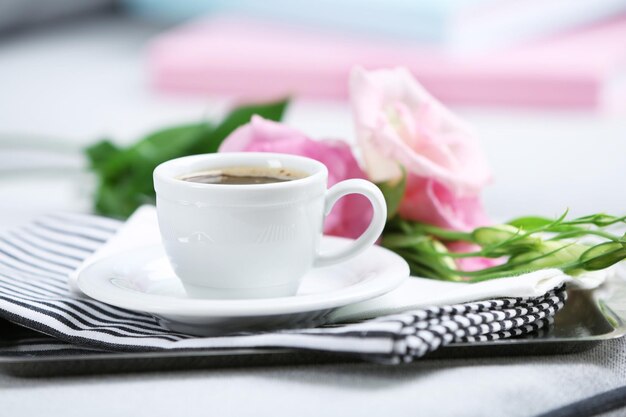 cup of coffee with flowers on tray on sofa in room
