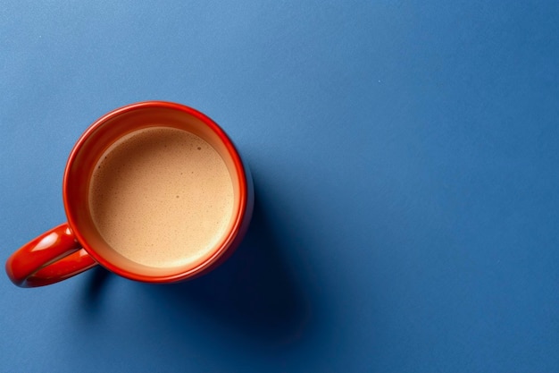 A cup of coffee with foam on blue background with copy space view from above isolated on studio background