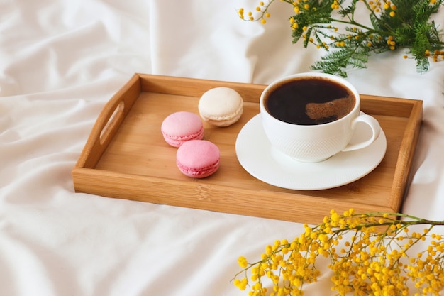 Cup of coffee with French macaroons on wooden tray