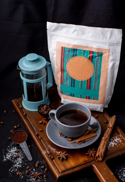 프렌치 프레스가 있는 커피 한 잔, 나무 판자와 검은색 배경에 브랜드가 없는 다양한 포장