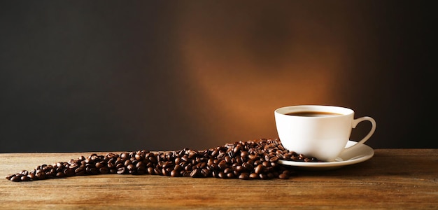 Cup of coffee with grains on wooden table on dark background