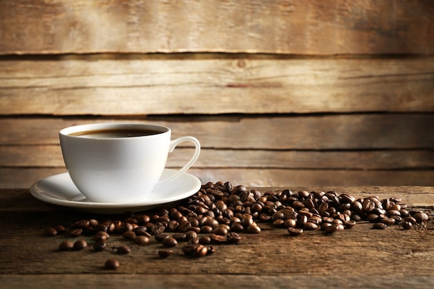 Tazza di caffè con grani sul tavolo di legno