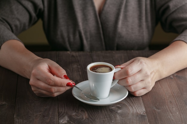 木製のテーブルに手でコーヒーカップ