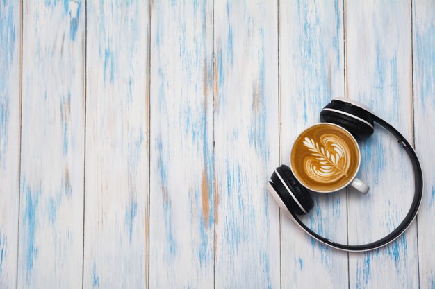 Una tazza di caffè con la cuffia sulla tavola di legno. vista superiore di arte del latte del caffè con lo spazio della copia. bere e concept art.